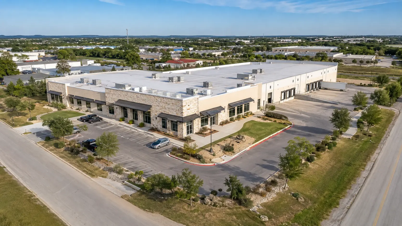 Representative aerial documentation image of a commercial office and warehouse property showing roof systems, parking, loading areas and site access