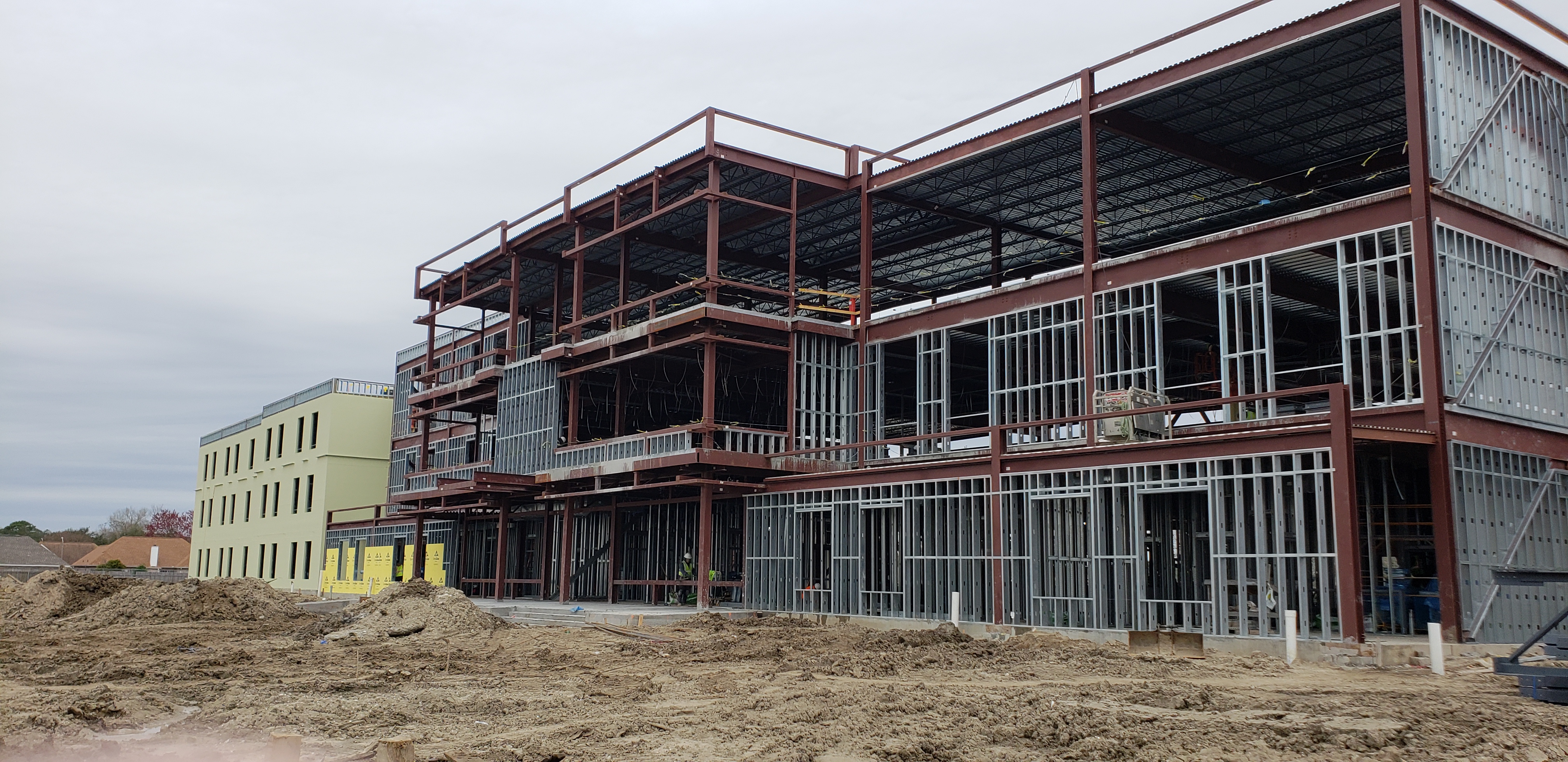 Active construction site with steel framing and earthwork in progress